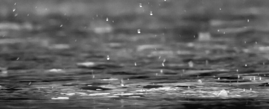 Regentropfen fallen auf Wasserfläche