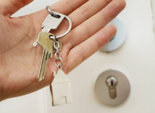 Hand mit Hausschlüssel vor einer Tür