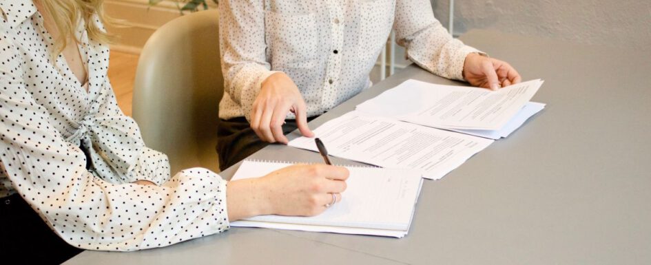 tow girls sitting signing an agreement